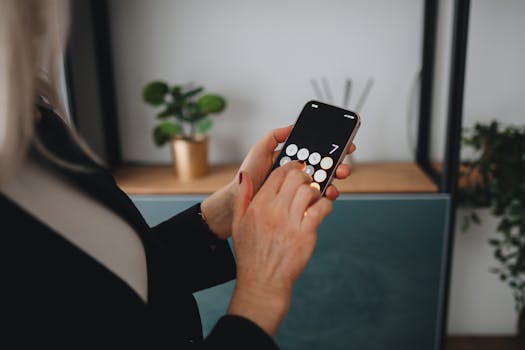 A person using a smartphone in a modern home setting, emphasizing technology and lifestyle.