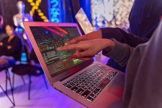 A vibrant scene with hands pointing at a computer with code on display, suggesting tech focus.