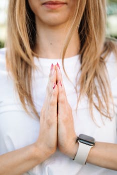 Close-up of a young woman performing yoga with folded hands and a smartwatch, symbolizing wellness and technology.