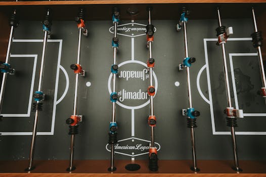 Top view of a foosball table with blue and red players, ready for play.