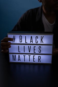 A lightbox displaying #BlackLivesMatter held by an individual, highlighting a message of empowerment.